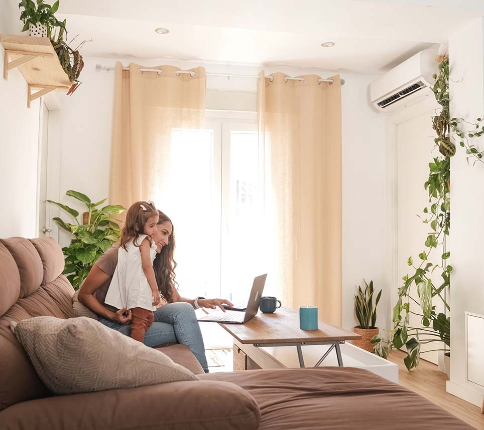 Girl with mother using netbook on sofa at home